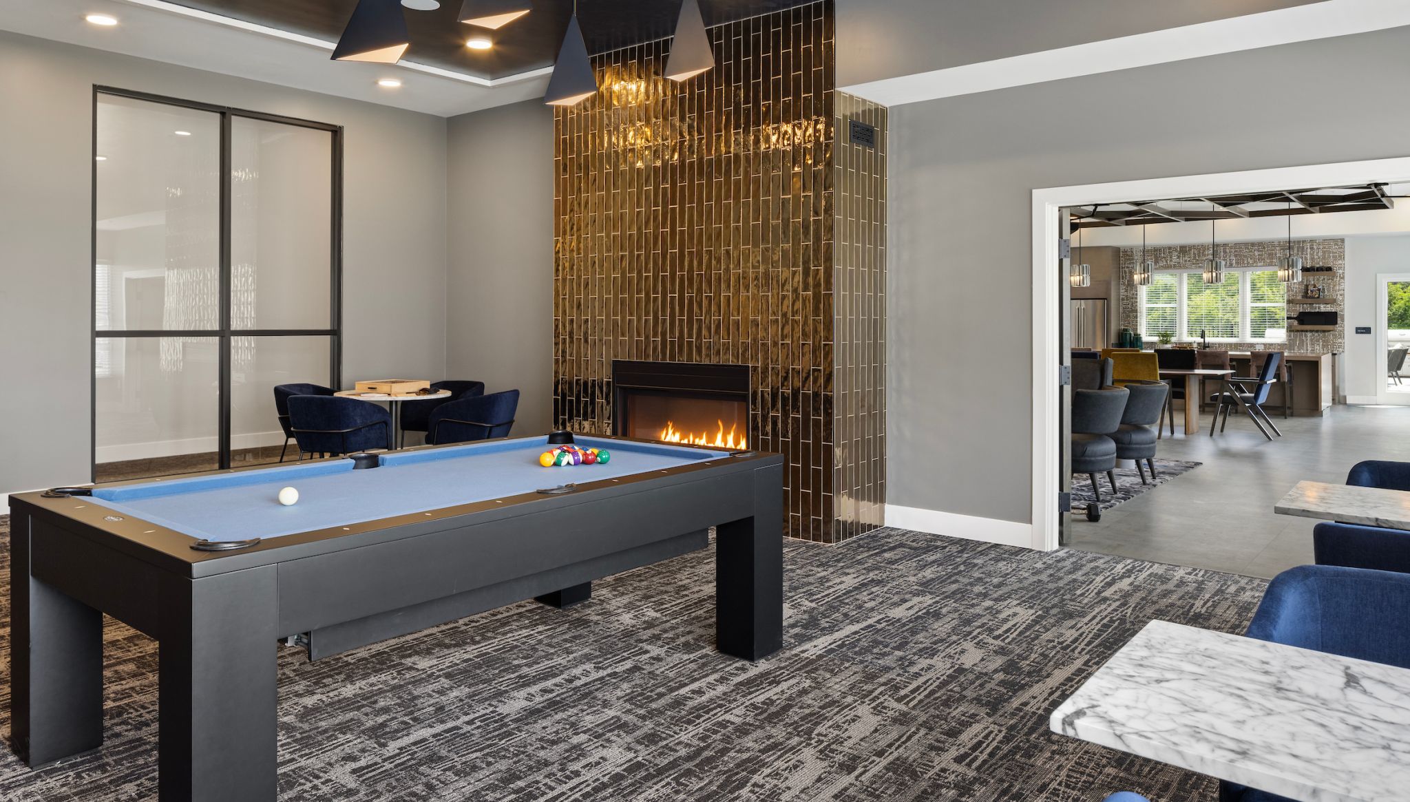 Slate apartments clubhouse game room with billiards table and seating.