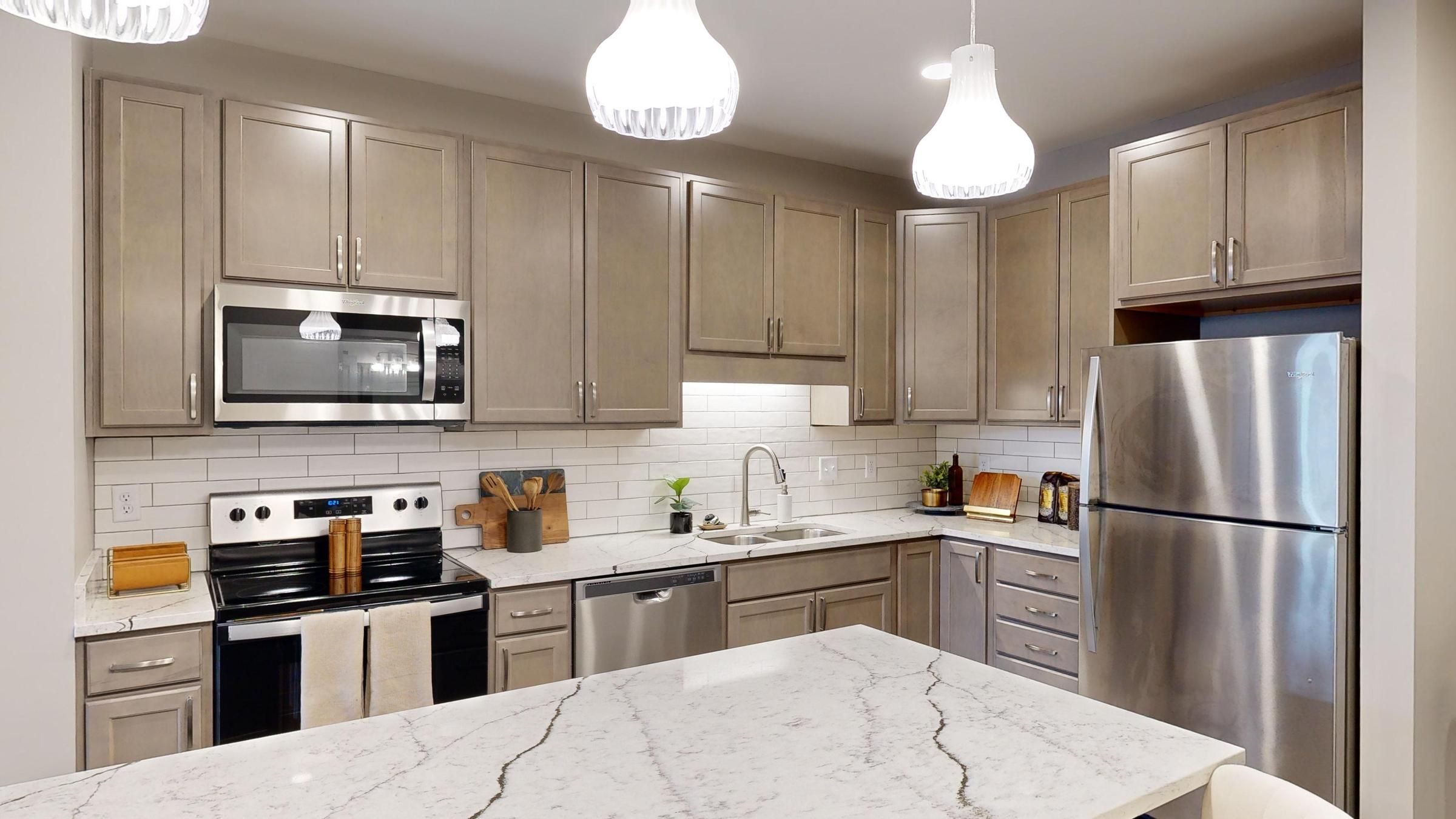 Slate property's sleek kitchen showcasing taupe cabinetry, white subway tile backsplash, and marble countertops.