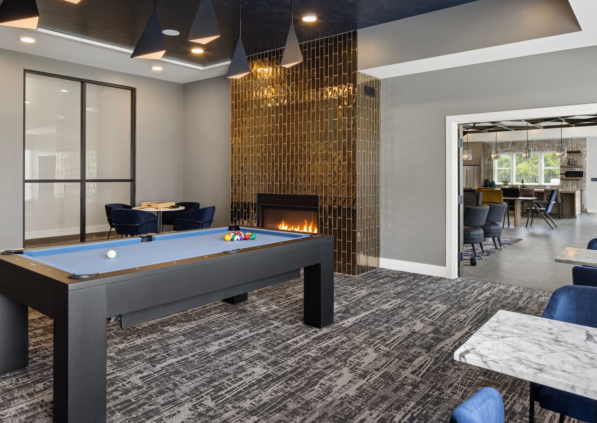 Slate apartments clubhouse game room with billiards table and seating.